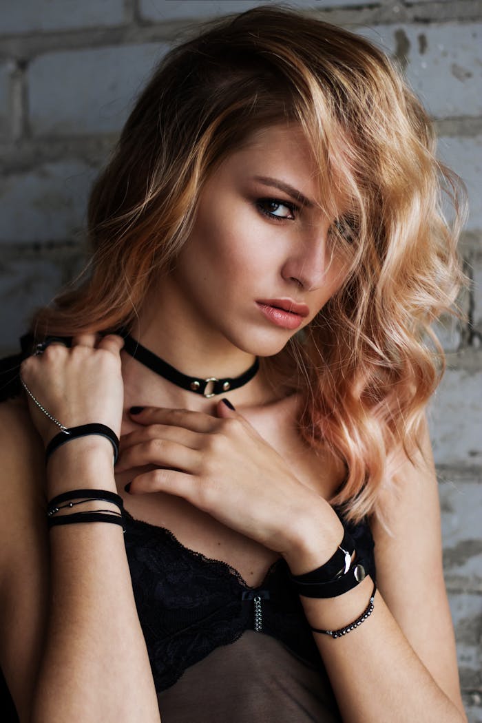 Facilities Close-up portrait of a stylish blonde woman in black lingerie against a brick wall.