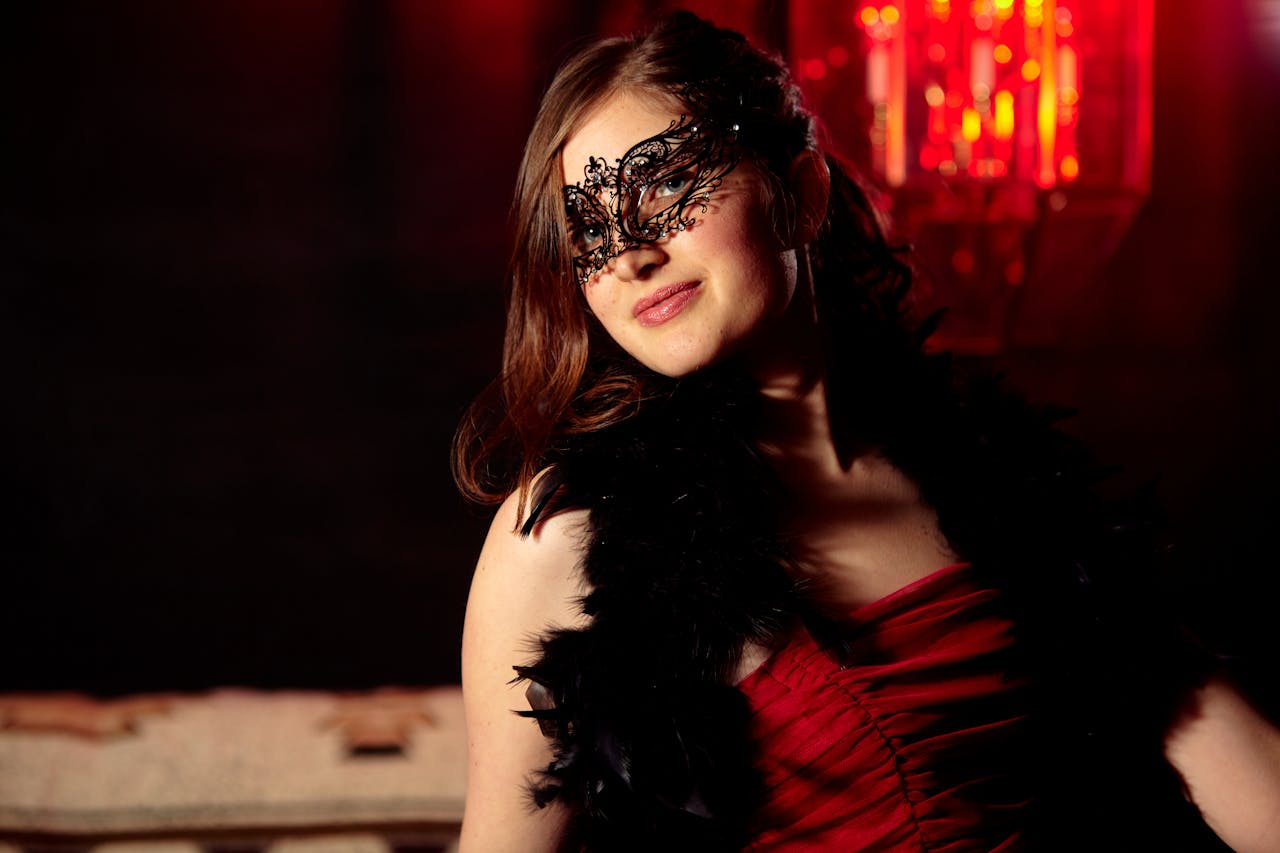 Glamorous woman in a masquerade mask at a mysterious night event with red lighting.